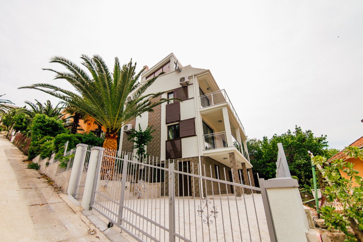 Teraslı ve avluda palmiye bulunan modern üç katlı villa, Krašići, Karadağ. Taş kaplamalı cephe.