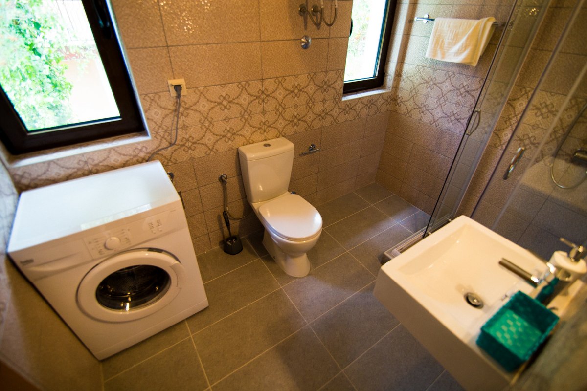 Krašići, Karadağ’daki villada duş kabini ve çamaşır makinesi bulunan banyo: modern fayans kaplaması.