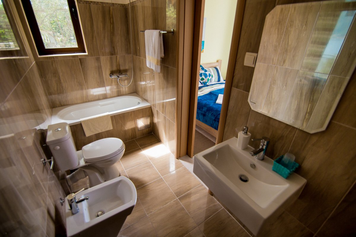 Krašići, Karadağ’daki villada, yatak odasına bakan, ahşap görünümlü fayanslı, küvetli ve bideli banyo.