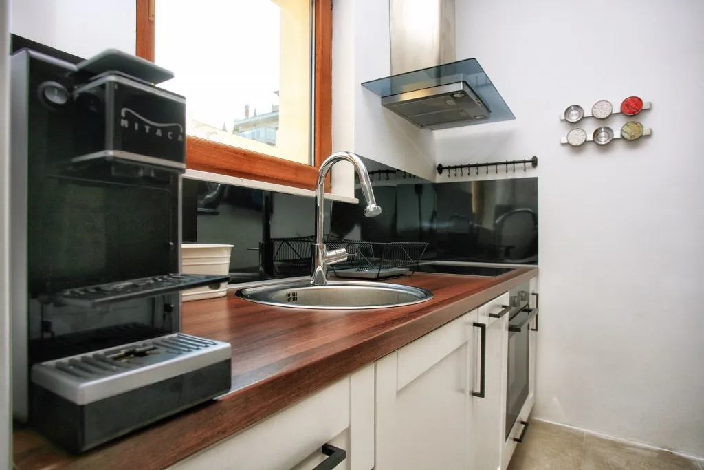Eine schicke moderne Küche mit Kaffeemaschine, Holzarbeitsplatten und weißen Schränken.