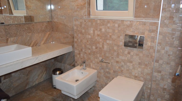 Modern bathroom in an apartment in Ljuta, Montenegro: tiled finish, wall-mounted fixtures, and a stone countertop.