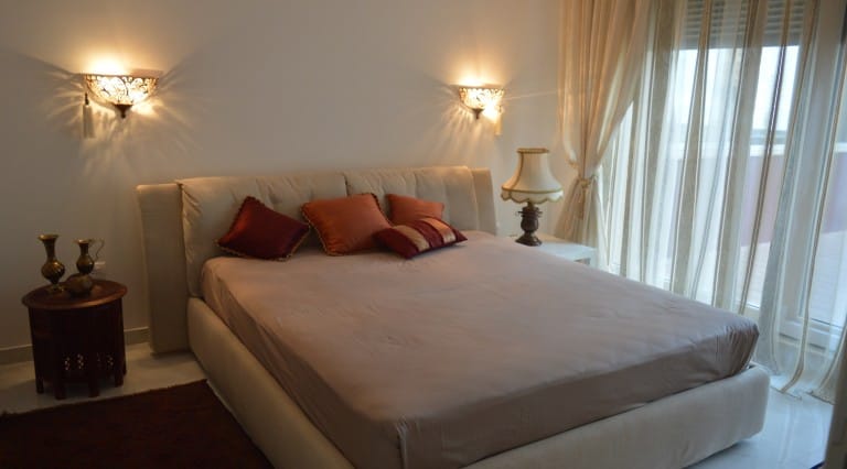 Cozy bedroom with a double bed in an apartment in Ljuta, Montenegro: stylish sconces, decor, and panoramic windows.