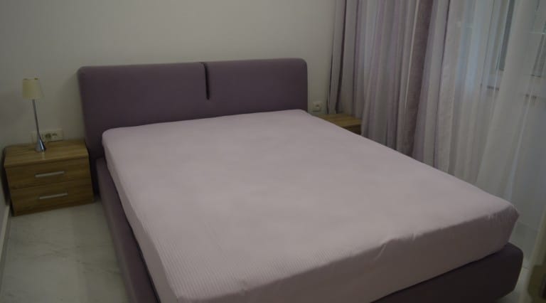 Cozy bedroom with a double bed in an apartment in Ljuta, Montenegro: modern furniture and a bright interior.