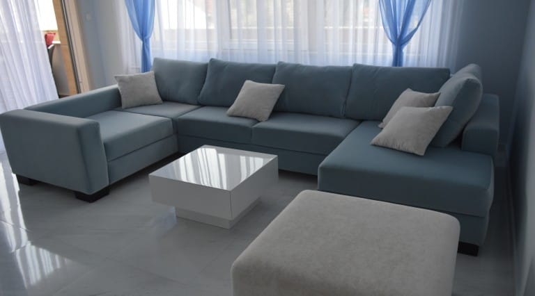 Living room with a blue corner sofa and a white coffee table in an apartment, Ljuta, Montenegro.