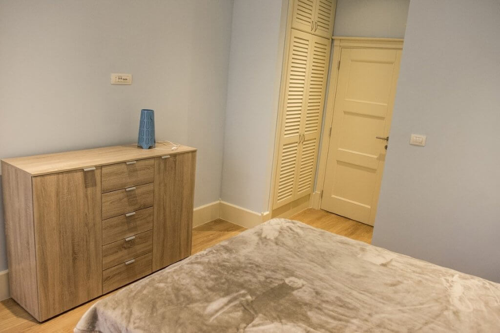 Schlafzimmer mit Holzkommode und Einbauschrank in der Villa, Stoliv, Montenegro. Helles Interieur mit Laminatboden.