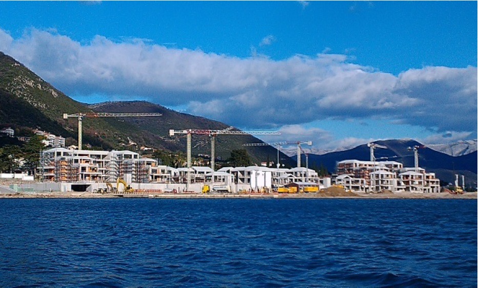 Construction d’un complexe résidentiel en première ligne de mer à Đenovići, Monténégro : vue sur le chantier avec des grues à tour.