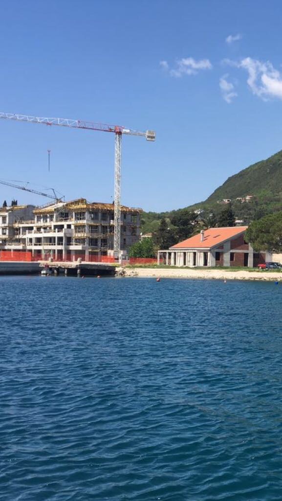 Complexe résidentiel en construction en première ligne de mer à Đenovići, Monténégro : vue sur le projet et le quai depuis l’eau.