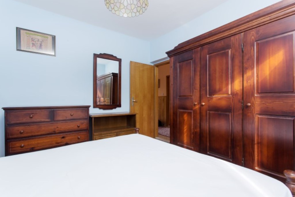 Schlafzimmer in einem Haus in Bijela, Montenegro: klassische Möbel aus dunklem Holz, ein Doppelbett und ein Spiegel an der Wand.