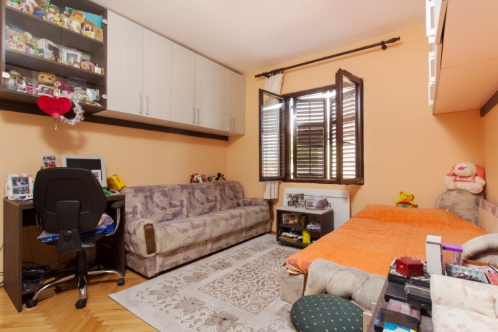 Kinderzimmer in einem Haus in Bijela, Montenegro: Bett, Sofa, Schreibtisch, Schränke und ein Fenster mit Holzläden.