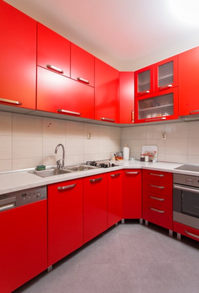 Helle Eckküche mit roten Fronten und eingebauten Geräten im Haus, Stadt Bijela, Montenegro.