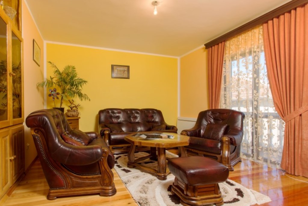 Wohnzimmer mit Ledermöbeln in einem Haus in Bijela, Montenegro: gelbe Wände, Holzboden und gemütliches Interieur.