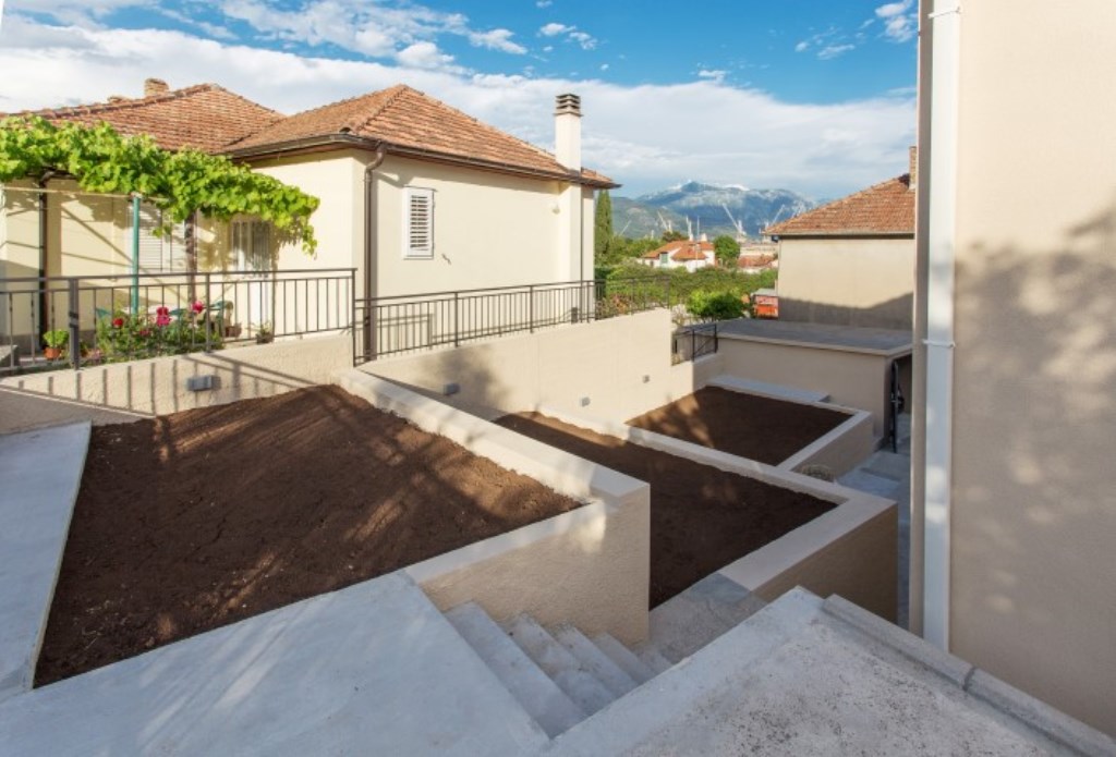 Terrassiertes Grundstück eines Hauses in Bijela, Montenegro, mit Blick auf die Berge und einem gepflegten Außenbereich.
