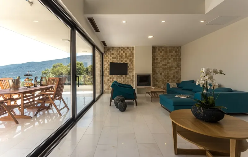 Geräumiges Wohnzimmer mit Kamin, blauem Sofa und Zugang zur Terrasse mit Bergblick