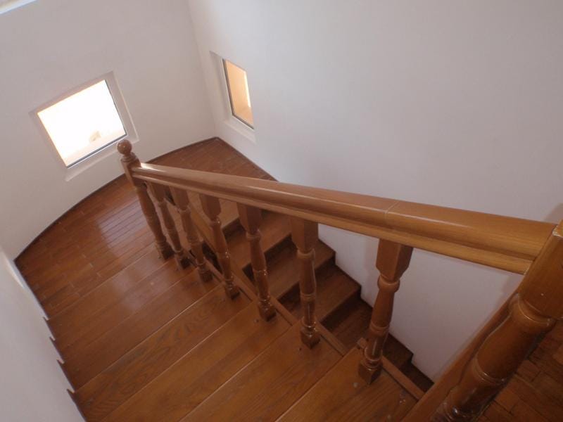Wooden staircase with carved railings in a house for sale in Baošići, Montenegro, bright interior with windows.