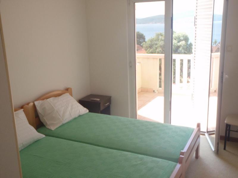 Bedroom with two beds and access to a balcony with sea view in a house, Baošići, Montenegro.