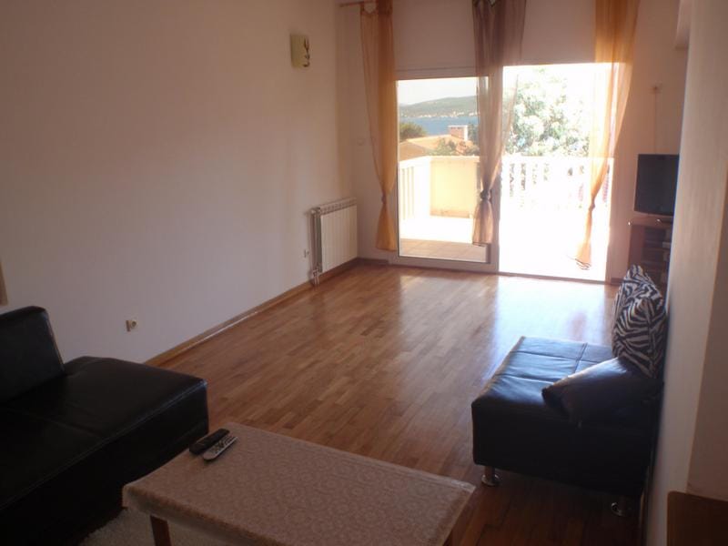 Living room with parquet flooring and access to a terrace with sea view in a house, Baošići, Montenegro. Furnished room with a sofa.