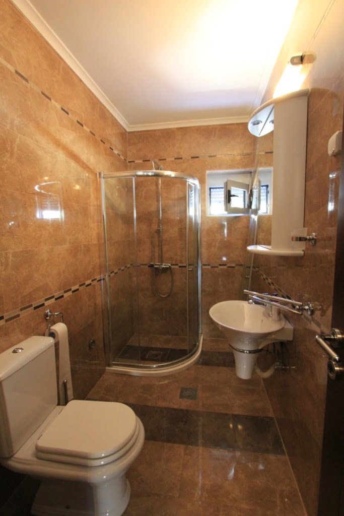 Łazienka z kabiną prysznicową i białą armaturą w mini-hotelu, Orahovac, Czarnogóra. Wykończenie beżowymi płytkami.