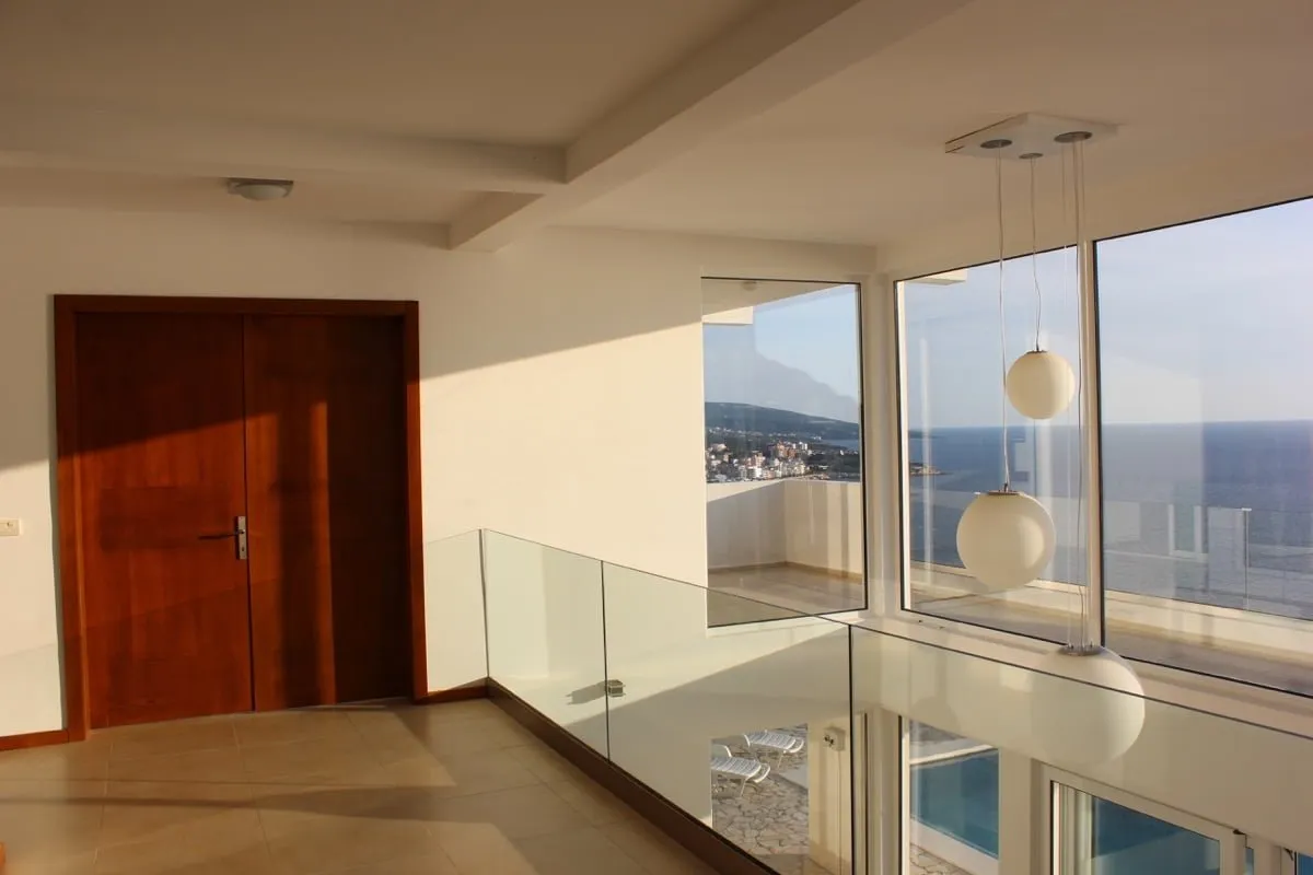 Modernes Wohnzimmer mit Panoramafenstern und Meerblick in einem Haus, Dobra Voda, Montenegro. Glasgeländer und Terrasse.