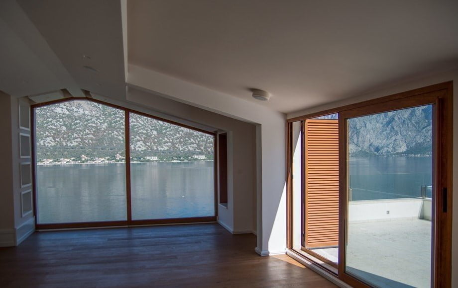 Living room with panoramic windows and a view of the Bay of Kotor, villa in Stoliv, Montenegro: modern interior and terrace.