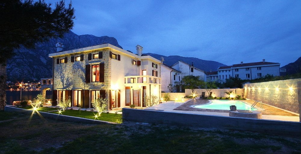 Karadağ, Prčanj’da deniz kenarında havuzlu, taş cepheli ve akşam aydınlatmalı iki katlı villa.