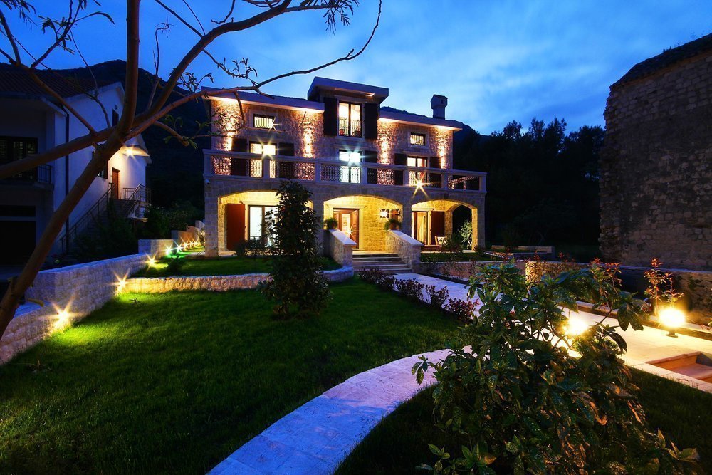 Karadağ, Prčanj’da aydınlatmalı ve bahçeli iki katlı taş villa: akşam saatlerinde cephe görünümü.