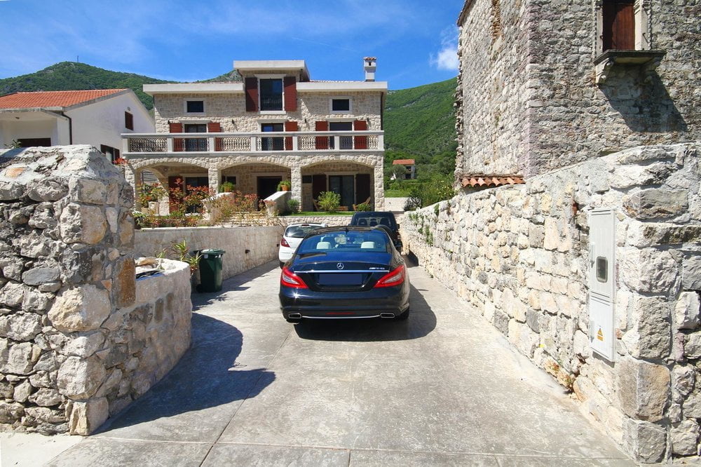 Prčanj, Karadağ'da taş villa: binanın cephesi, teras, araçlı otopark ve dağ manzarası.