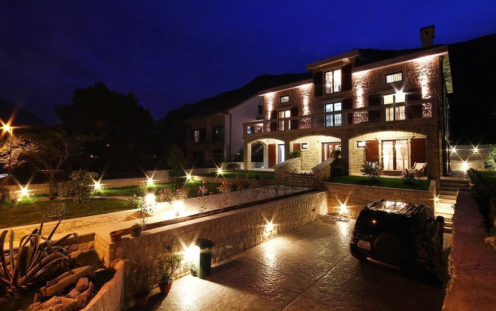 Prčanj, Karadağ’da cephe aydınlatmalı, teraslı ve otoparklı iki katlı taş villa, gece görünümü.