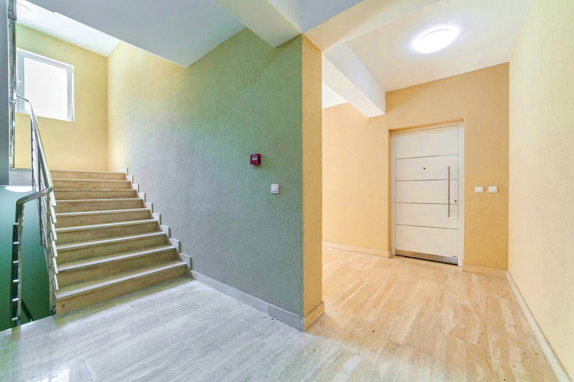 Heller Hauseingang mit Treppe und Eingangstür in einer Wohnanlage, Kotor, Montenegro. Moderne Innenausstattung.