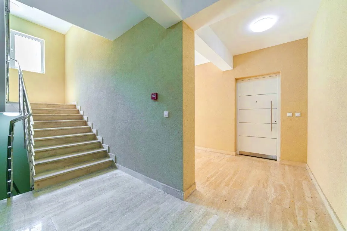 Heller Hauseingang mit Treppe und Eingangstür in einer Wohnanlage, Kotor, Montenegro. Moderne Innenausstattung.