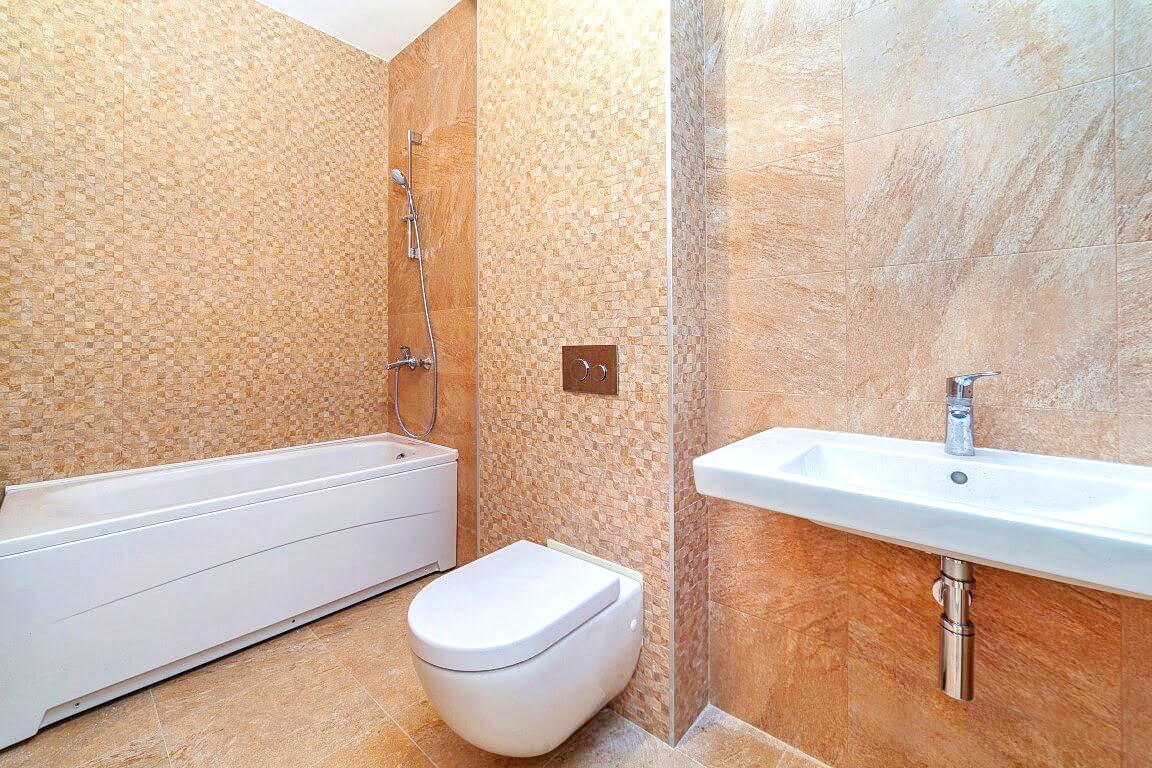 Modernes Badezimmer mit weißer Sanitärkeramik und beigen Fliesen in einer Wohnung, Kotor, Montenegro.