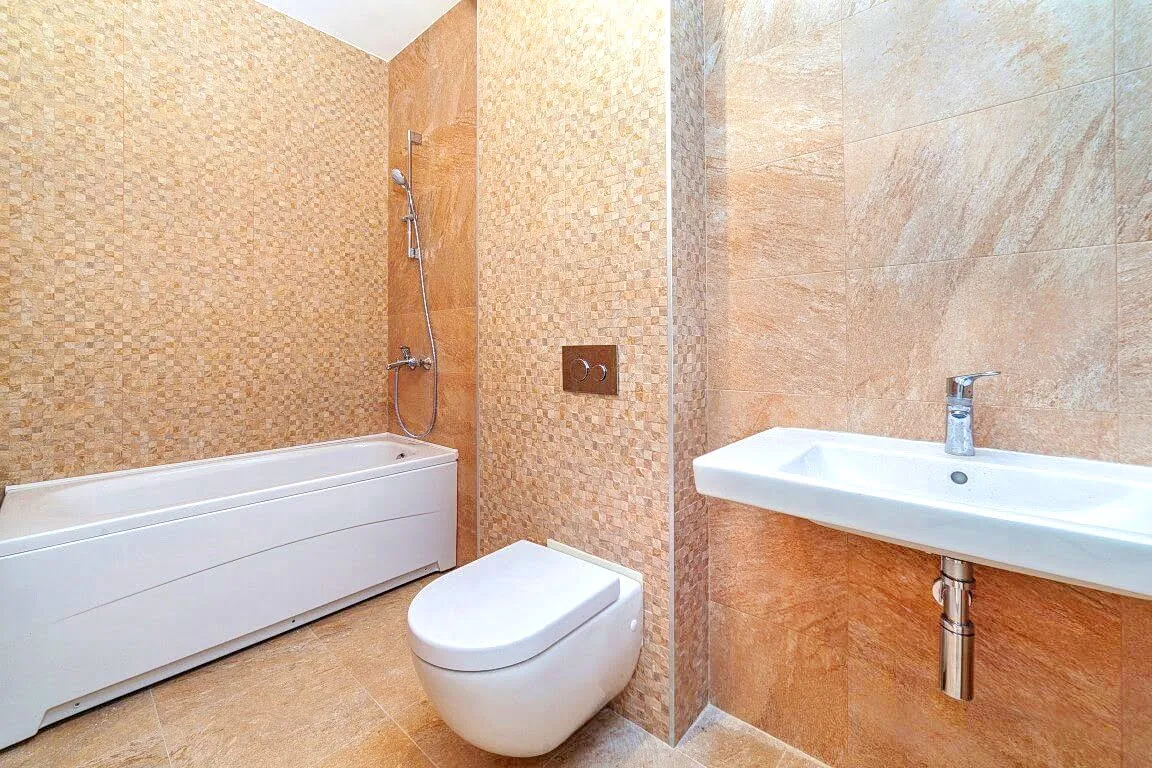 Modernes Badezimmer mit weißer Sanitärkeramik und beigen Fliesen in einer Wohnung, Kotor, Montenegro.
