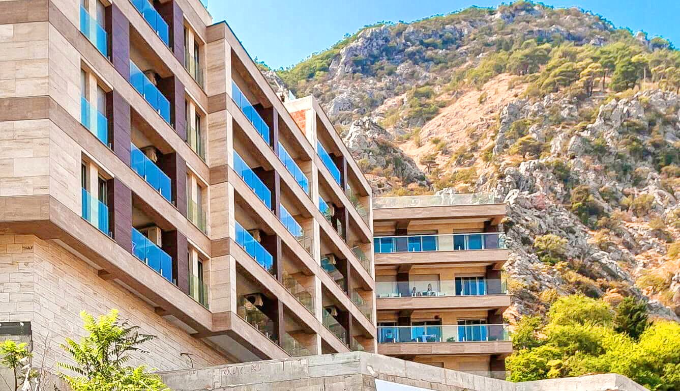 Moderner Wohnkomplex mit Terrassen am Fuße der Berge in Kotor, Montenegro: Blick auf die Fassade des Gebäudes.