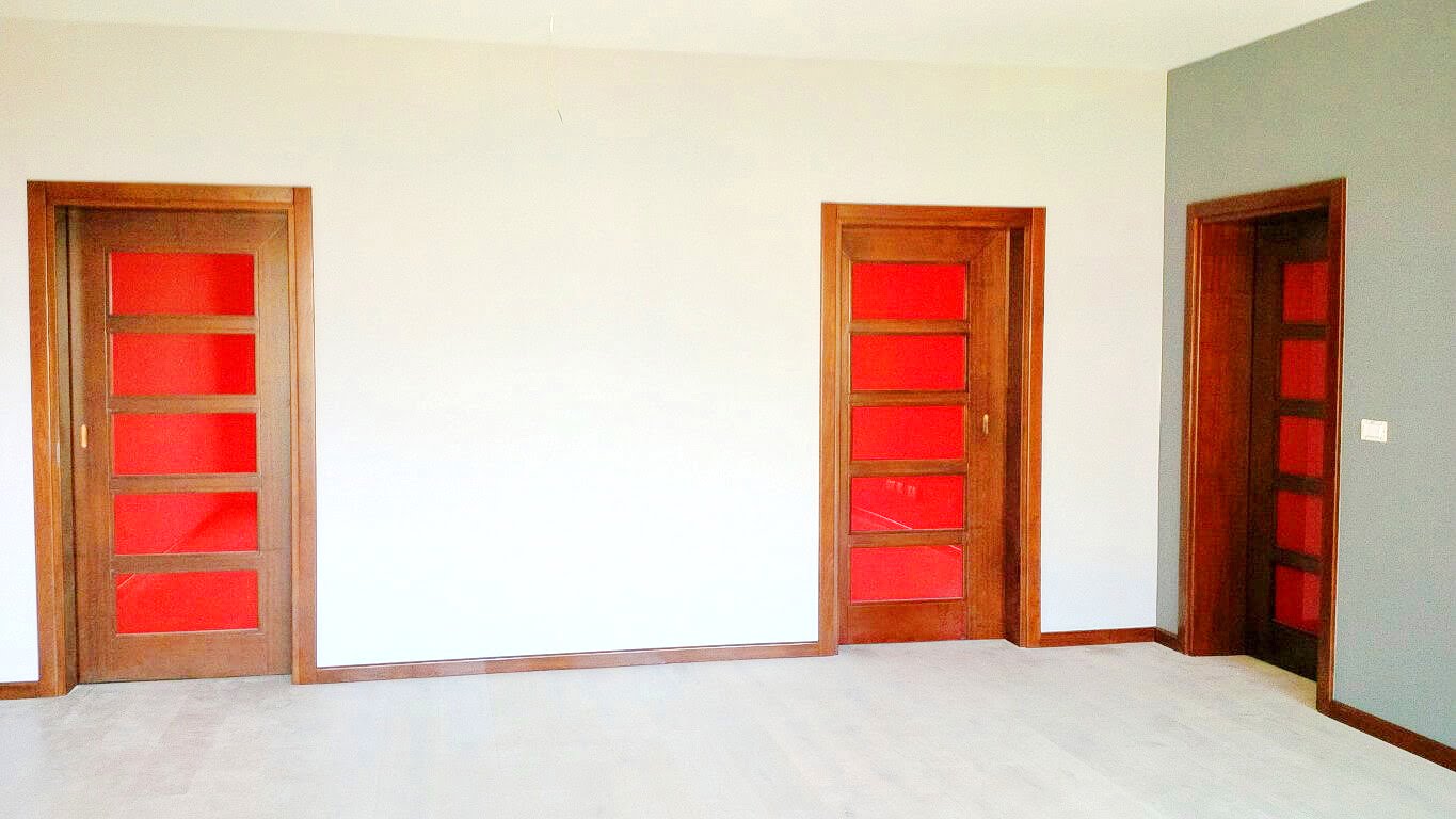 Innenraum des Wohnzimmers in einer Wohnung, Kotor, Montenegro: helle Wände, Holztüren mit roten Glaseinsätzen.