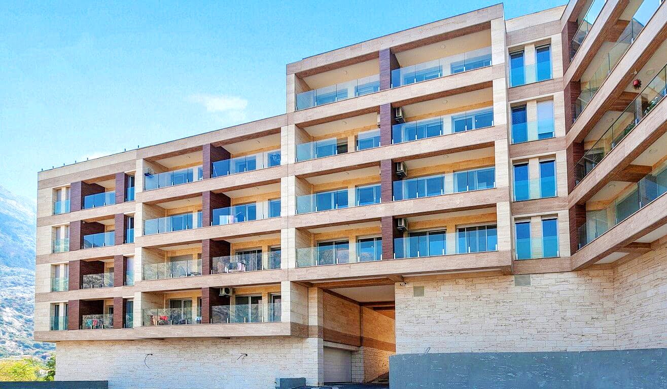 Moderner Wohnkomplex mit Balkonen und Steinverkleidung der Fassade in der Bucht von Kotor, Montenegro.