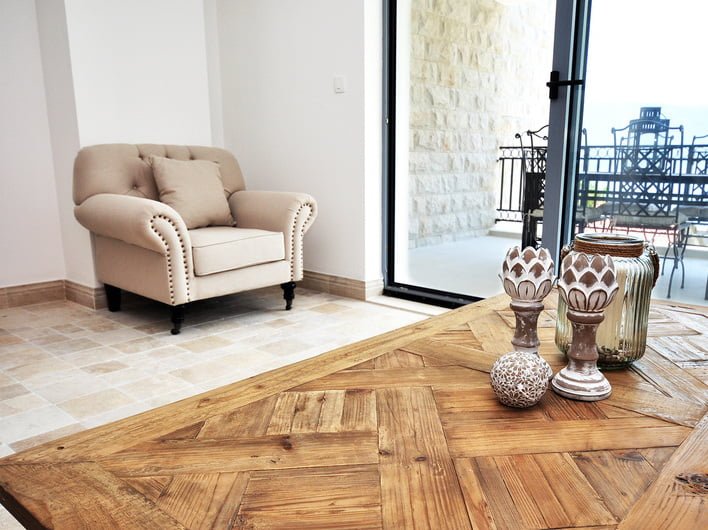 Gemütliches Wohnzimmer in einer Wohnung in Risan, Montenegro: beiger Sessel, Holztisch und Ausgang zur Terrasse mit Aussicht.