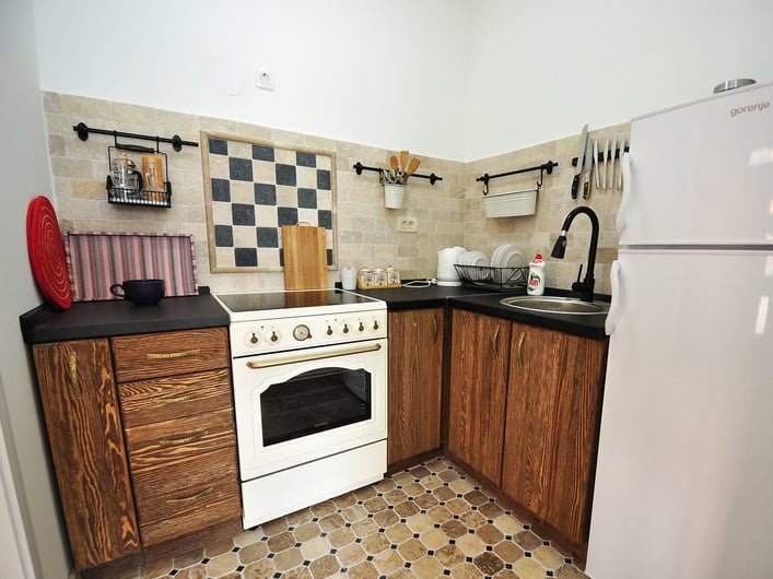 Gemütliche Küche mit Holzfronten und weißem Herd in einer zum Verkauf stehenden Wohnung in Risan, Montenegro.