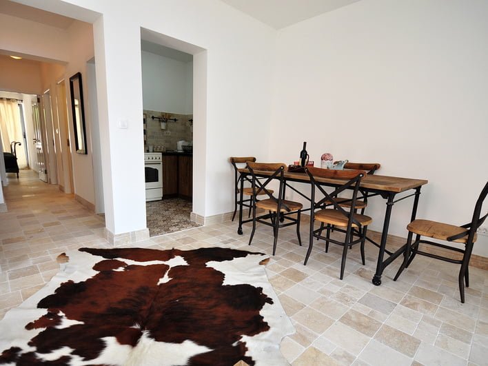 Wohnzimmer mit Essbereich und Teppich aus Tierfell in einer zum Verkauf stehenden Wohnung in Risan, Montenegro. Helles Interieur mit Fliesen.