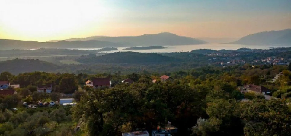 Panoramablick auf Berge, Meer und das Tal mit verstreuten Häusern und dichten grünen Wäldern