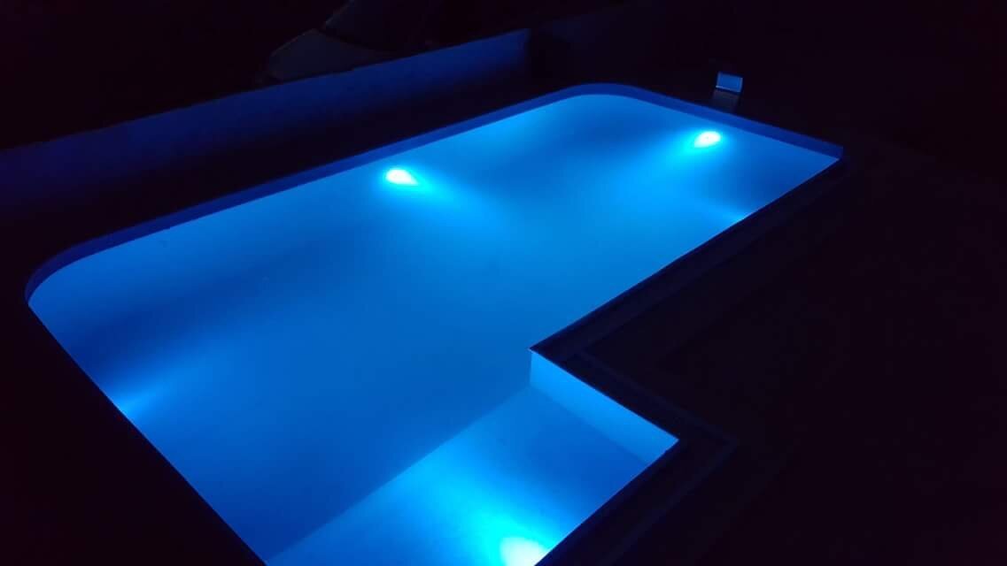 Otwarty basen z neonowym podświetleniem na terenie willi w mieście Bar, Czarnogóra, widok nocą.