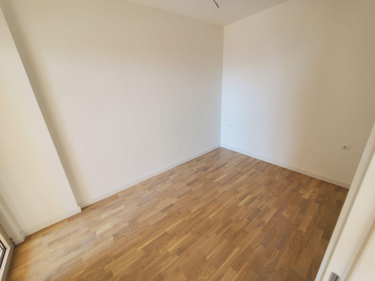Prazna soba sa laminatom na podu i belim zidovima