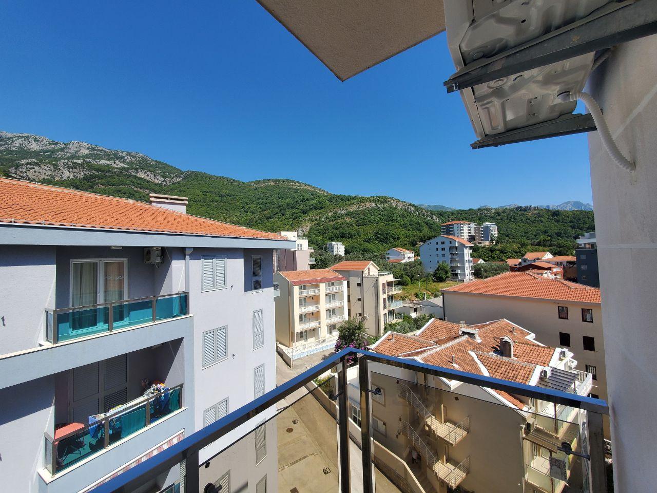 Pogled sa balkona na susedne zgrade i planine po sunčanom danu