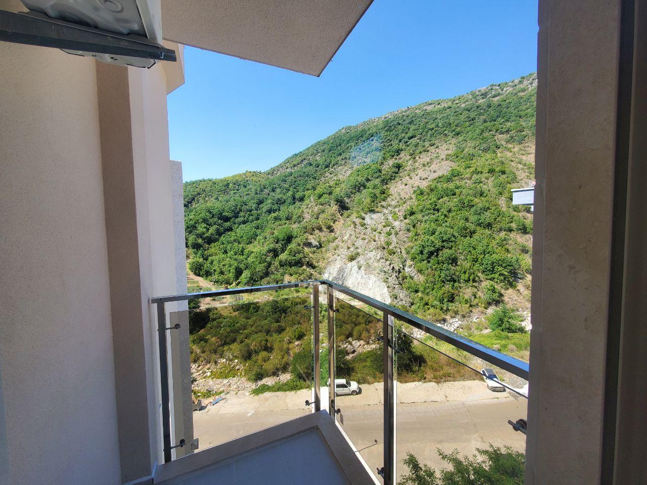 Balkon sa staklenom ogradom i pogledom na planinu.