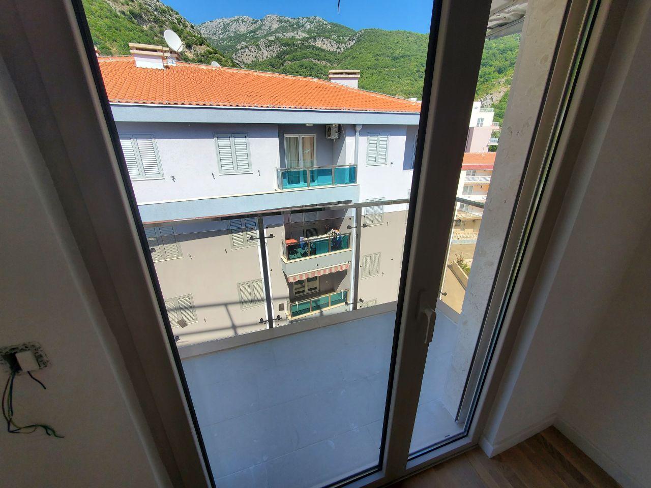 Pogled kroz staklena vrata na balkon i susedne zgrade
