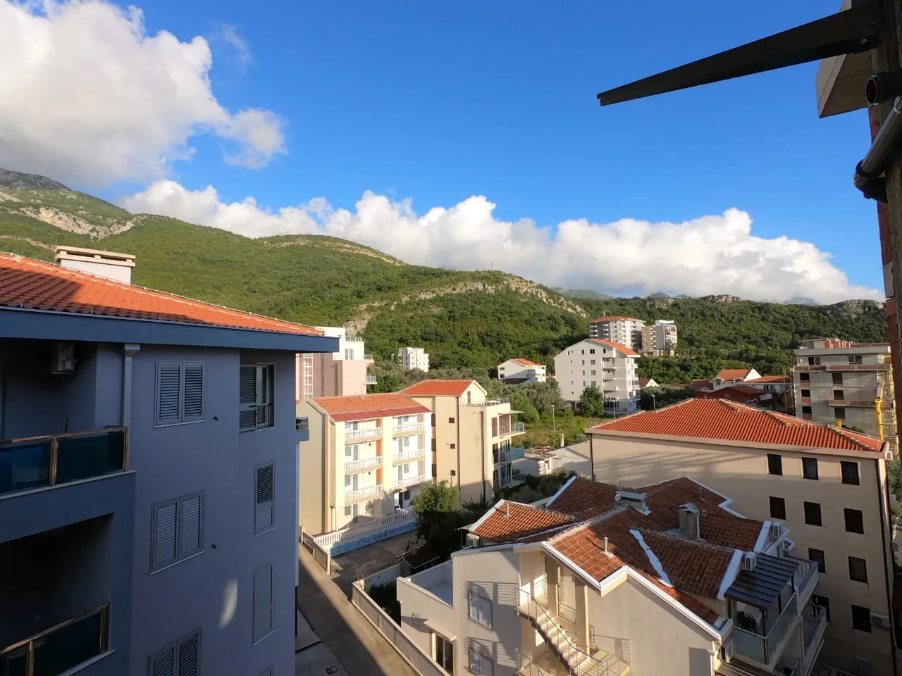 Вид с балкона на город, горы и облачное небо.