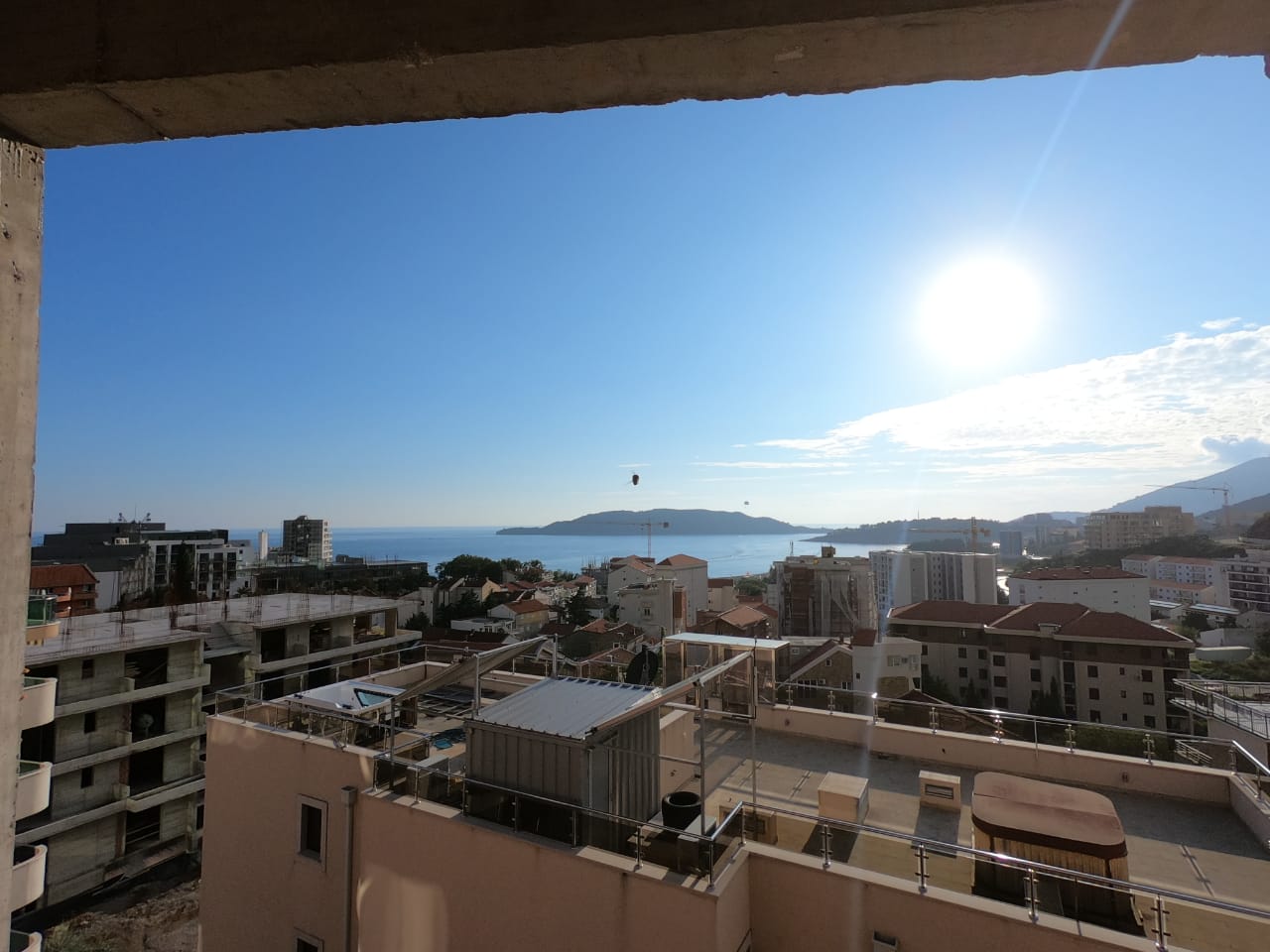 Pogled na grad i more sa balkona visokog sprata na sunčan dan.