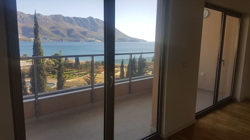 Karadağ, Bečići’deki dairenin oturma odasından görünüm: panoramik pencereler, deniz ve dağ manzaralı teras.