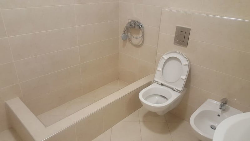 Karadağ, Bečići’deki bir dairede modern banyo: bej fayanslar, asma klozet, биде ve duş alanı.