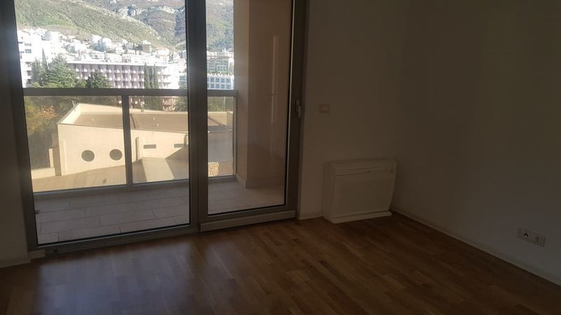 Bečići, Karadağ’daki dairede parke, panoramik pencere ve balkona çıkışı olan aydınlık oturma odası.