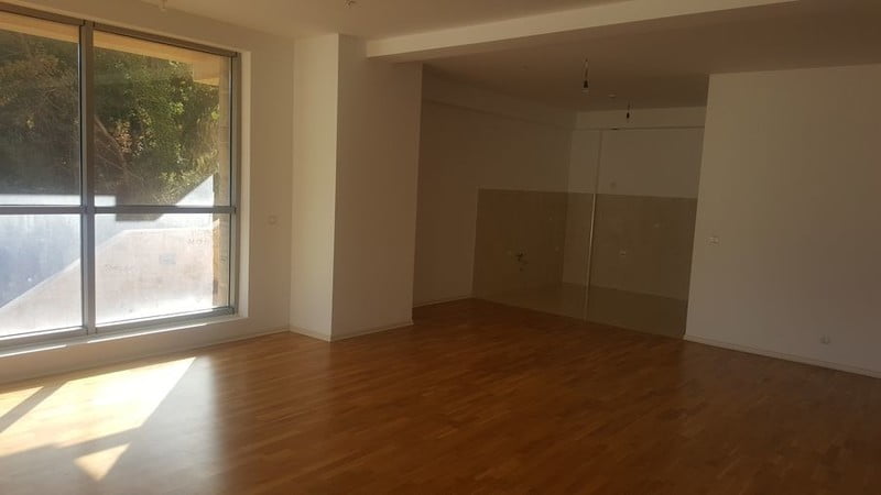 Parkeli ve panoramik pencereli aydınlık oturma odası, Becici, Karadağ’daki yeni dairede. Mobilyasız.