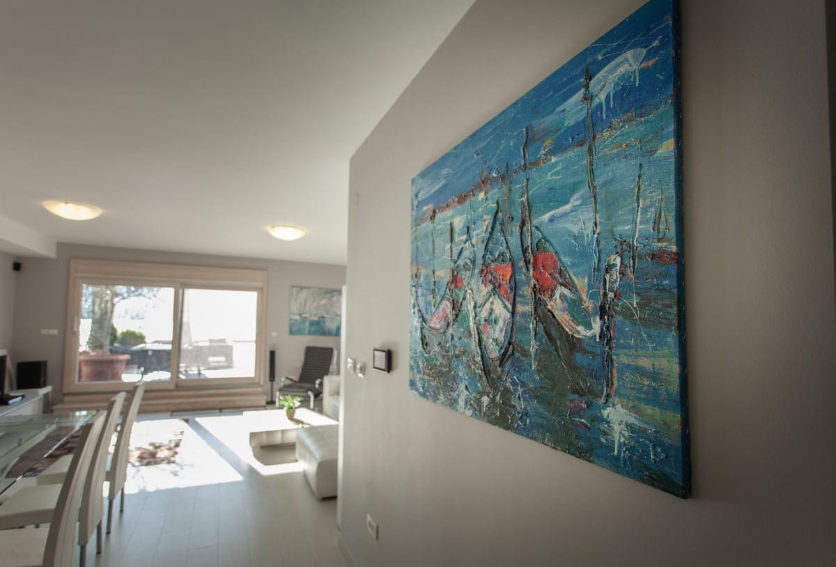 Salon moderne avec tableau dans un appartement à Ljuta, Monténégro : intérieur lumineux, fenêtre panoramique et coin repas.